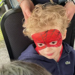 A toddler with his face painted as Spiderman