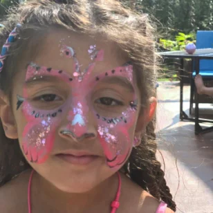 A girl with a sparkly pink butterfly facepainting